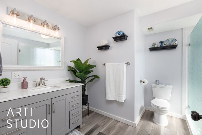 Full bath with wood finished floors, vanity, toilet, a shower, and baseboards | Image 23
