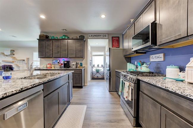 Kitchen featuring appliances with stainless steel finishes, healthy amount of natural light, dark brown cabinets, light stone countertops, and recessed lighting | Image 18
