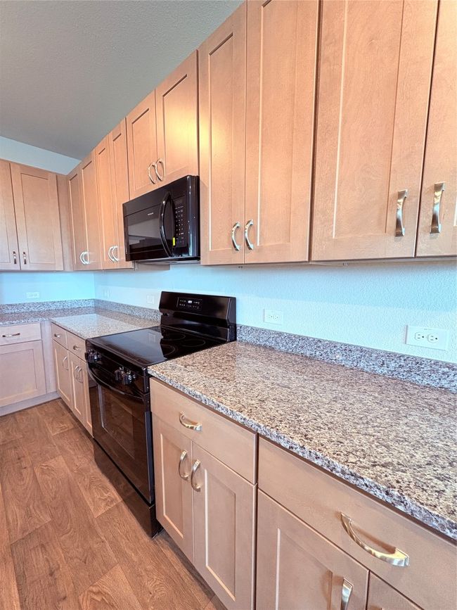 Kitchen featuring light stone countertops, stove, and light wood-style floors | Image 8