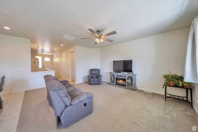 Carpeted living room featuring a ceiling fan, visible vents, recessed lighting, and a textured ceiling | Image 11