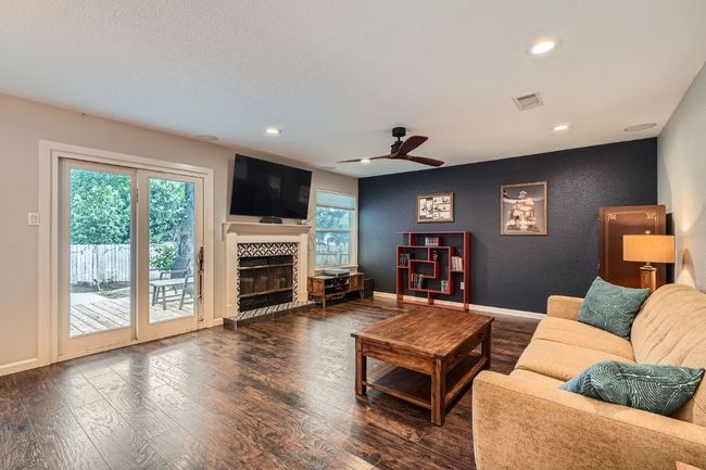 Living room with wood finished floors, healthy amount of natural light, a fireplace, recessed lighting, and a ceiling fan | Image 10