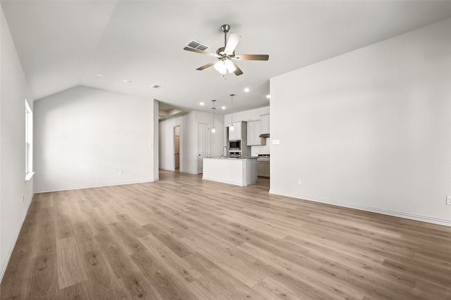 Unfurnished living room with a ceiling fan, recessed lighting, light wood finished floors, and vaulted ceiling | Image 11