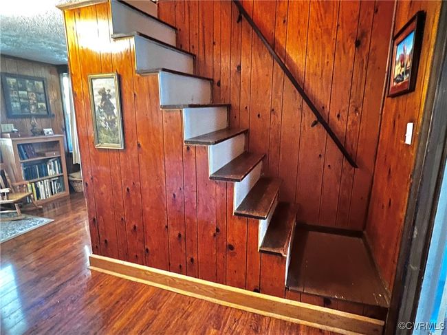 Stairway with a textured ceiling, wooden walls, and hardwood / wood-style flooring | Image 34