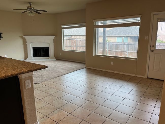Unfurnished living room with plenty of natural light, ceiling fan, light tile patterned floors, and a glass covered fireplace | Image 5