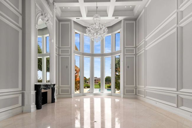 Formal living room features a floor to ceiling window view and healthy amount of natural light, towering ceiling, a chandelier, and beam ceiling | Image 7