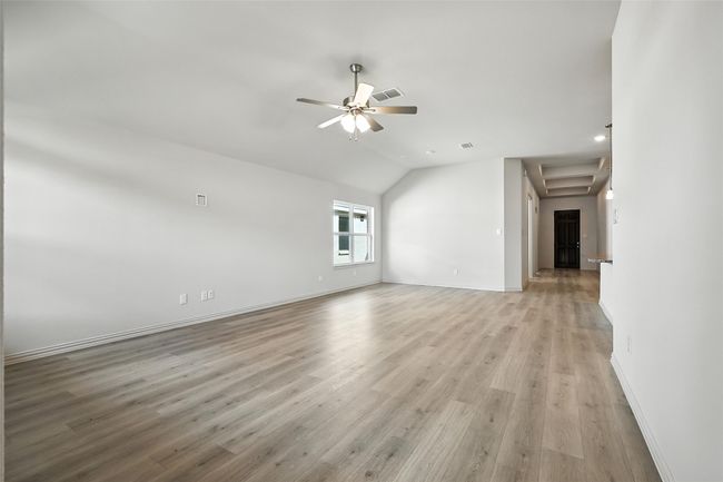Unfurnished living room featuring a ceiling fan, vaulted ceiling, and light wood finished floors | Image 13