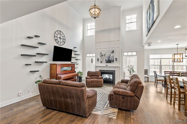 Living room featuring a notable chandelier, wood-type flooring, a healthy amount of sunlight, and a high ceiling | Image 8