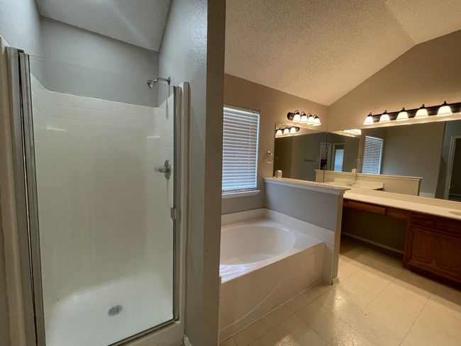 Full bathroom featuring a shower stall, a garden tub, lofted ceiling, vanity, and a textured ceiling | Image 8