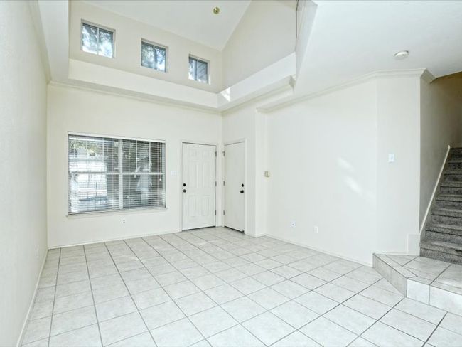 Unfurnished living room featuring stairs, a high ceiling, light tile patterned floors, and plenty of natural light | Image 5