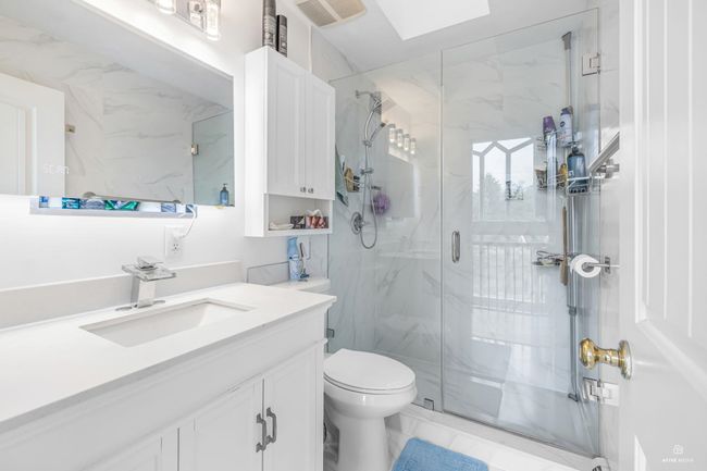 Full bathroom featuring a marble finish shower, toilet, marble finish flooring, and vanity | Image 22