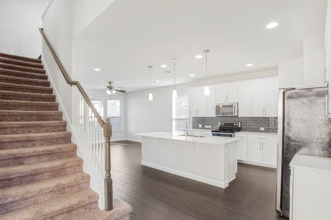 Kitchen with stainless steel appliances, recessed lighting, dark wood-style floors, backsplash, and white cabinetry | Image 9