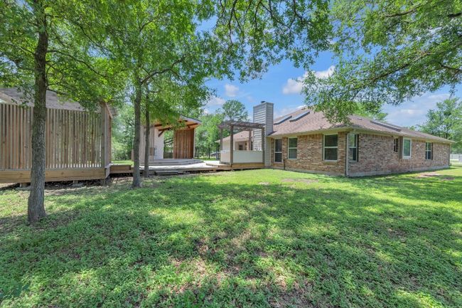 View of grassy yard featuring a wooden deck and a pergola | Image 6