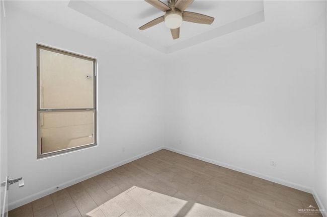 Empty room featuring a raised ceiling, ceiling fan, and wood finished floors | Image 5