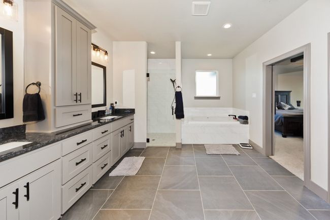 Ensuite bathroom featuring double vanity, a garden tub, visible vents, a sink, and tiled shower | Image 25