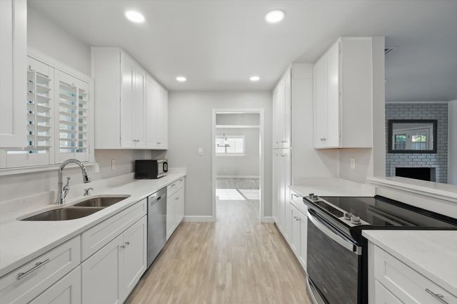 Kitchen featuring white cabinets, appliances with stainless steel finishes, a sink, and light wood-style floors | Image 9