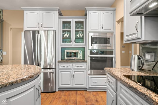 kitchen featuring light stone countertops, a toaster, appliances with stainless steel finishes, light wood finished floors, and range hood | Image 29