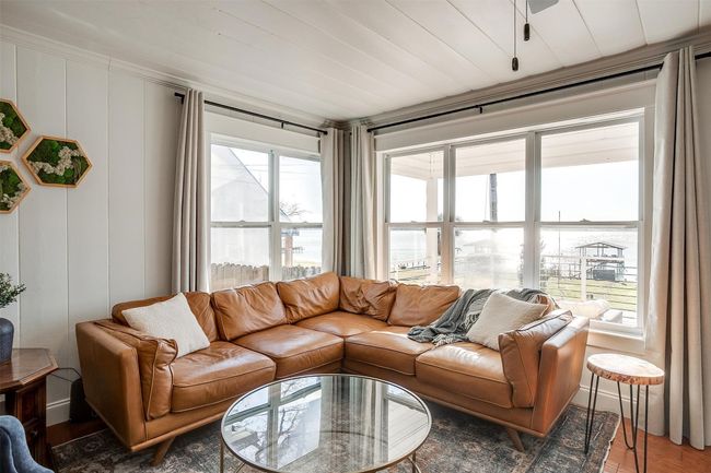 Living area with plenty of natural light, wood finished floors, and a decorative wall | Image 11