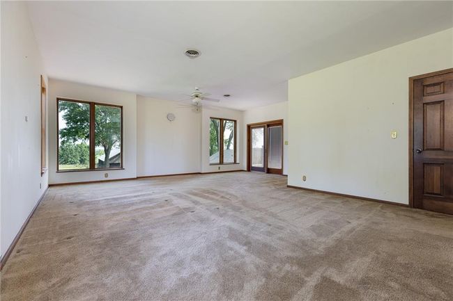 Carpeted empty room featuring ceiling fan and a healthy amount of sunlight | Image 44