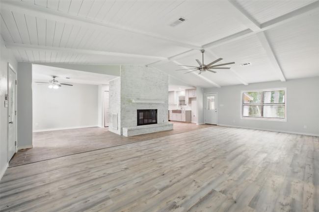 Natural light fills this spacious living area, where vaulted ceilings and a white brick surround create texture, height, and comfort. | Image 4
