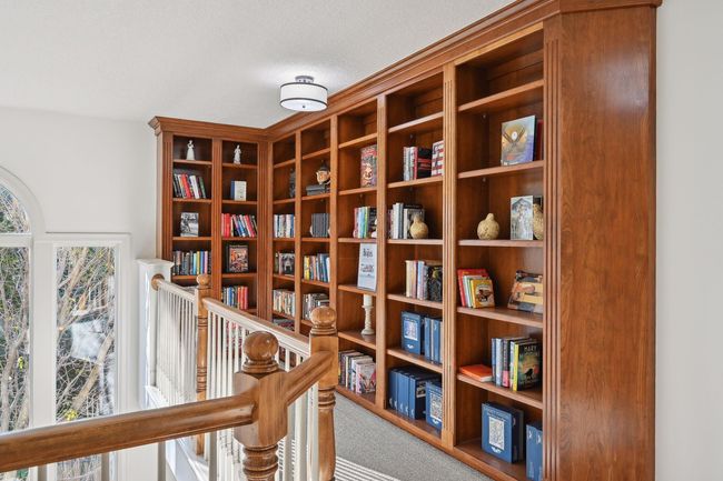 Built in bookshelves in upper level loft overlooks the dining room. | Image 34
