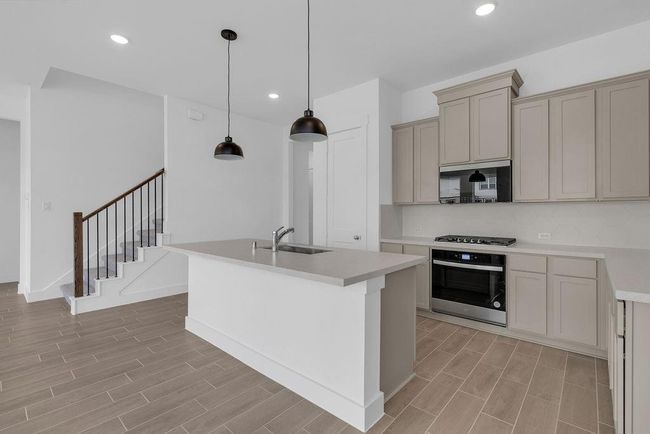 In this open concept kitchen, the stairway is tucked away, to not disrupt the open flow of this home. | Image 5