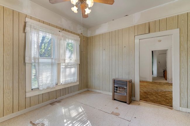Unfurnished room featuring tile patterned floors, wood walls, a ceiling fan, and heating unit | Image 17
