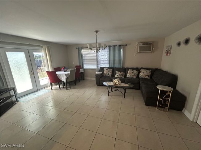 Living room featuring a chandelier, plenty of natural light, light tile patterned floors, and an AC wall unit | Image 4