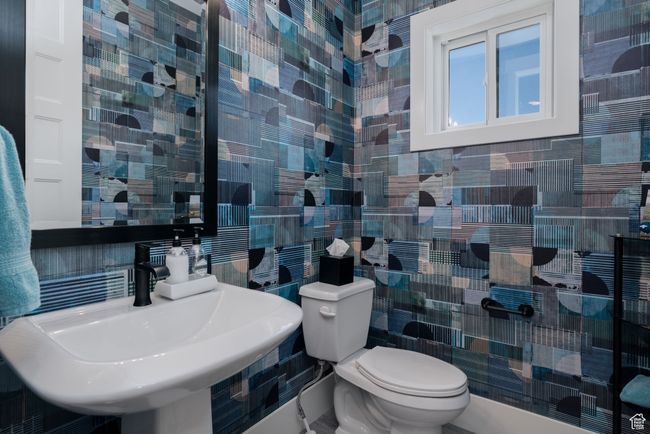 Half bathroom with tile walls, a sink, toilet, and backsplash | Image 26