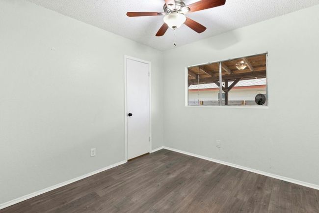 Empty room with dark wood-style floors, a textured ceiling, and ceiling fan | Image 19