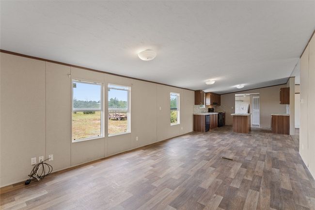 Unfurnished living room with vinyl finished floors and vaulted ceiling | Image 12
