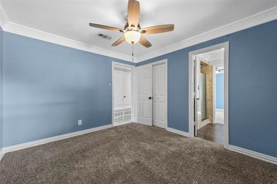 Unfurnished bedroom featuring dark colored carpet, crown molding, and ceiling fan | Image 3