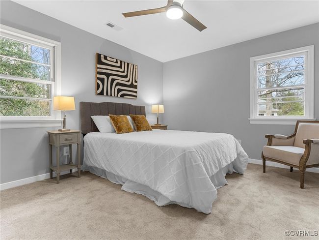 Bedroom featuring a ceiling fan, light colored carpet, visible vents, and baseboards | Image 24