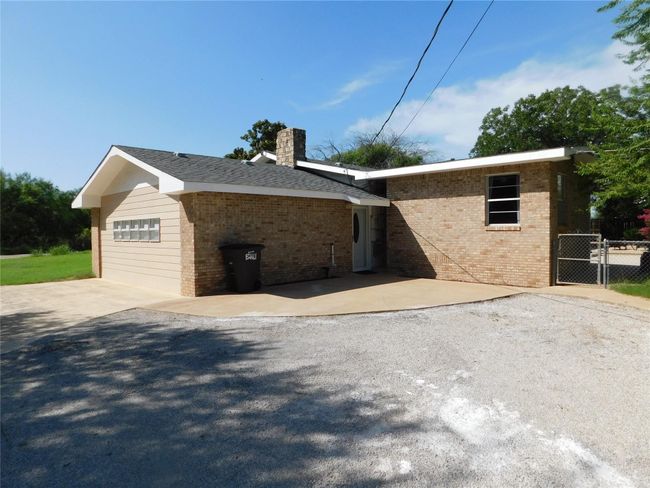 View of front of house featuring brick siding, driveway, a chimney, and a garage | Image 33