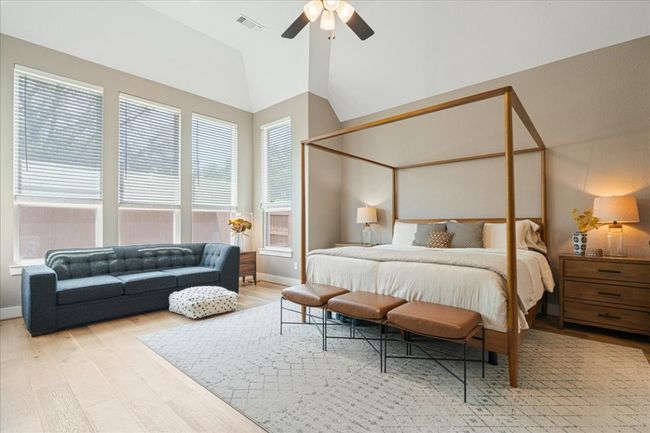 Bedroom featuring wood finished floors, lofted ceiling, multiple windows, and a ceiling fan | Image 17