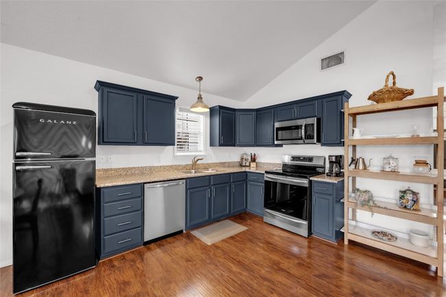 Kitchen with a sink, appliances with stainless steel finishes, lofted ceiling and dark wood-style flooring | Image 10