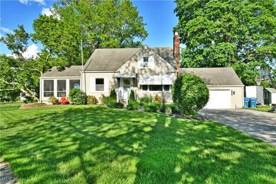 Cape cod home with a garage, a front yard, and a shed | Image 1