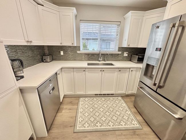 Kitchen featuring stainless steel appliances, light wood finished floors, white cabinets, and tasteful backsplash | Image 7