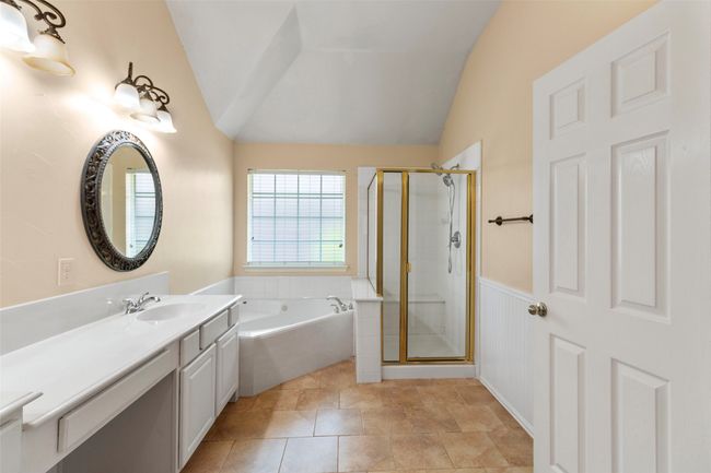 Bathroom featuring lofted ceiling, a shower stall, vanity, a garden tub, and a wainscoted wall | Image 16