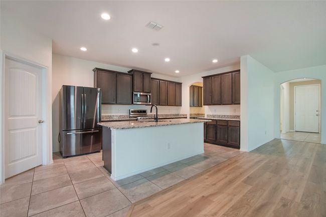 Kitchen with stainless steel appliances, arched walkways, dark brown cabinets, and recessed lighting | Image 12