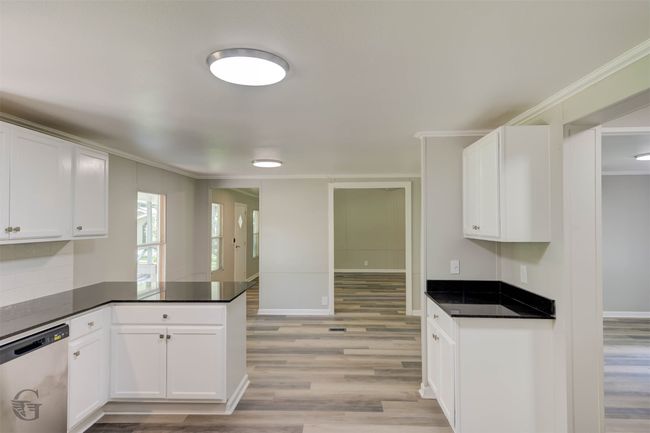 Kitchen with dishwasher, ornamental molding, a peninsula, light Luxury Vinyl floors, and white cabinets | Image 13
