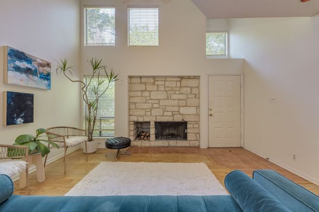Living area with a high ceiling, baseboards, and a fireplace | Image 4