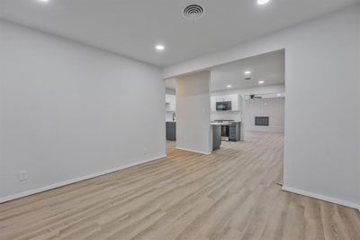 Unfurnished living room featuring a brick fireplace and light hardwood / wood-style floors | Image 3