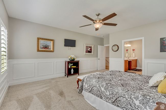 Carpeted bedroom featuring a wainscoted wall, ensuite bathroom, a ceiling fan, and a decorative wall | Image 16