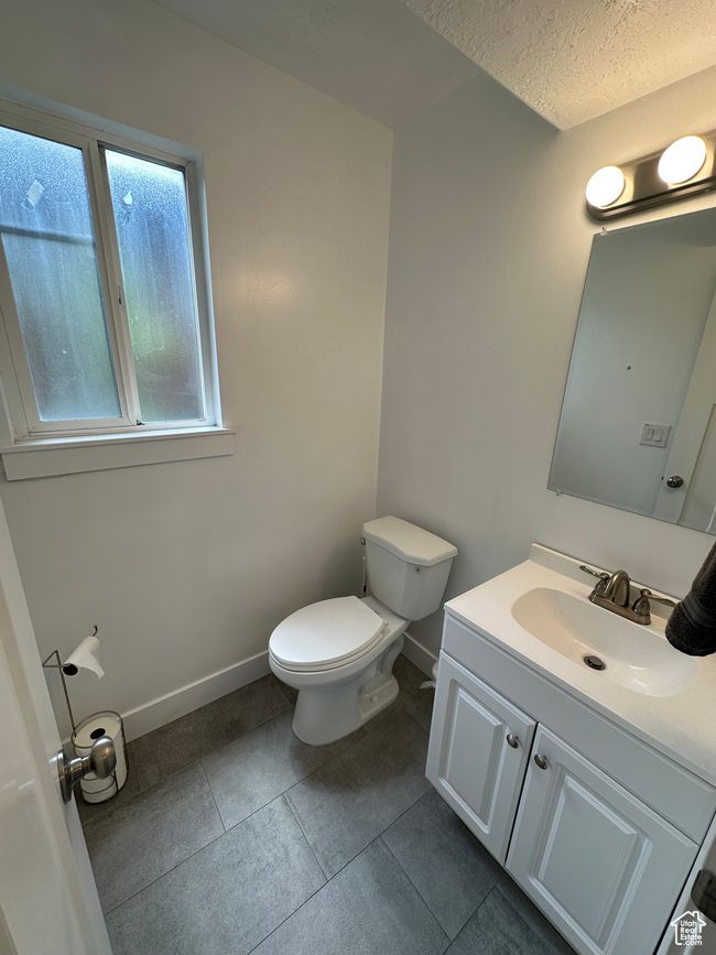 Bathroom with toilet, vanity, tile patterned floors, baseboards, and a textured ceiling | Image 14