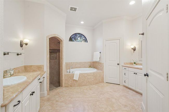 Luxurious primary bath featuring a relaxing jacuzzi and a sleek walk-in shower. | Image 26