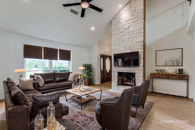 Living area featuring ceiling fan, high vaulted ceiling, a stone fireplace, light wood-style floors, and recessed lighting | Image 4