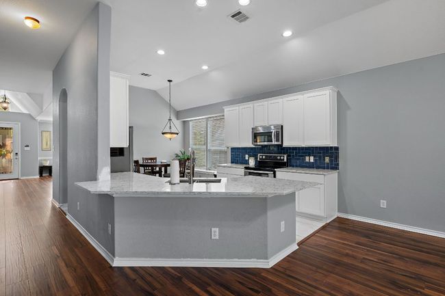 Kitchen featuring appliances with stainless steel finishes, a sink, vaulted ceiling, and white cabinetry | Image 7