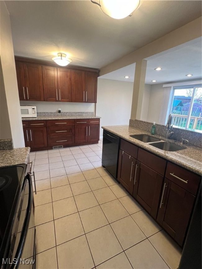 Kitchen featuring granite countertops, dishwashing machine, range, sink, and light tile floors | Image 20