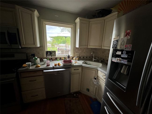Kitchen with appliances with stainless steel finishes, a sink, tasteful backsplash, light countertops, and dark wood-style floors | Image 16