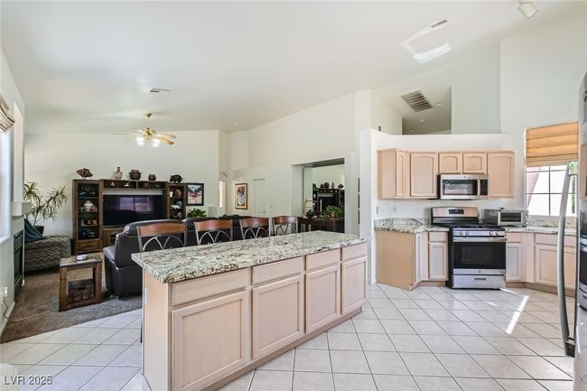 Kitchen featuring appliances with stainless steel finishes, light tile patterned floors, open floor plan, a kitchen island, and ceiling fan | Image 8